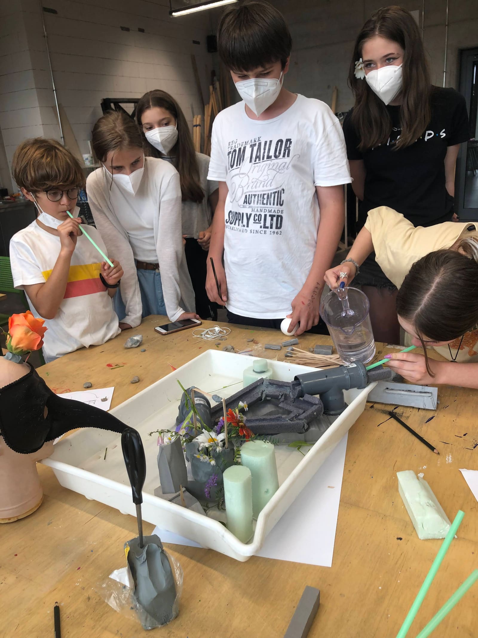 Students gathered around a worktable during Boot Camp, using materials and tools to prototype a project under time pressure.
