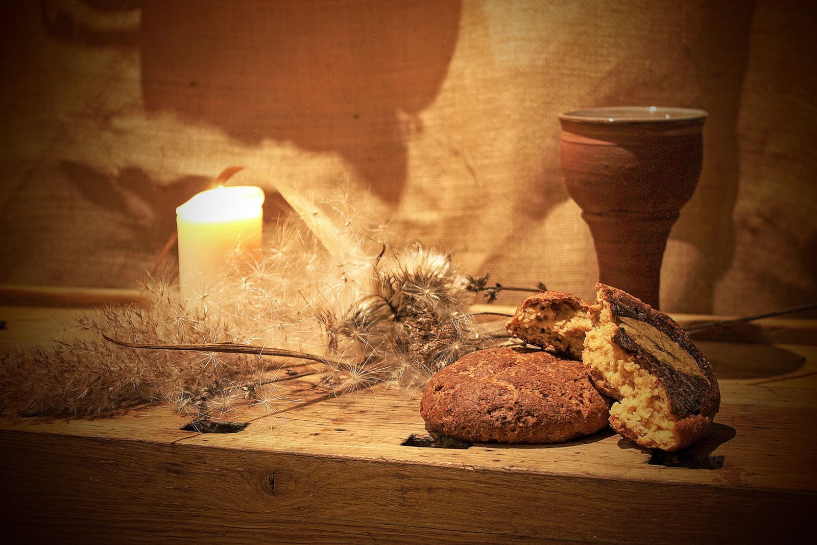 A still life of bread, a candle, and a clay cup staged as part of the Food-Art Collective's food memory and publication work.
